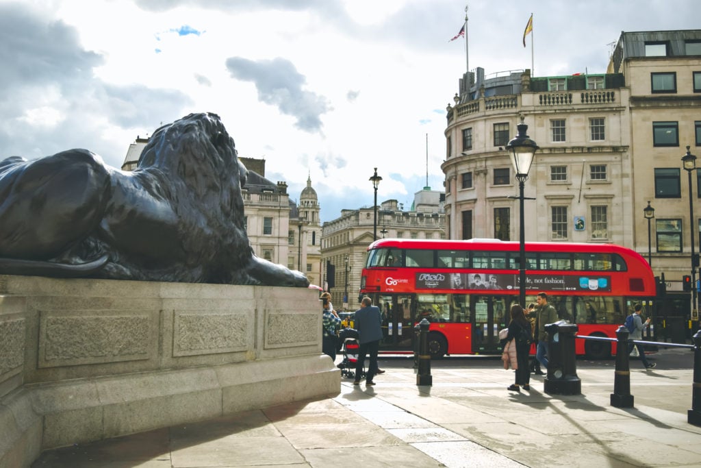 Trafalgar Square London with lion statues and red double-decker bus.