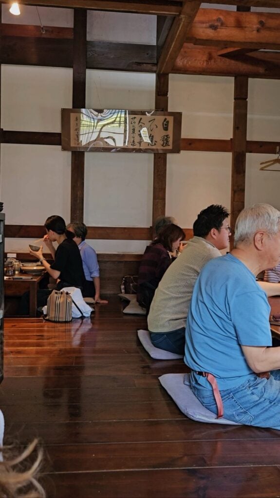 Steaming bowls of handmade udon served on tatami mats at Kamachiku, a converted stone warehouse restaurant in Tokyo.